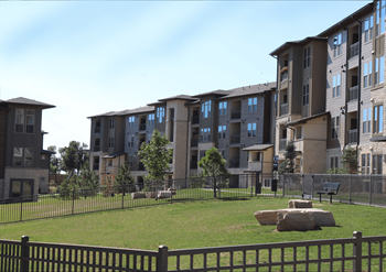 Apartment complex with a fenced in grassy area in front.